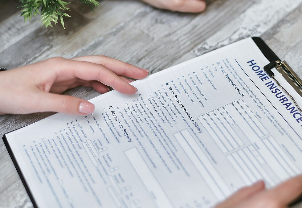 Close-up of a person filling out a home insurance form on a clipboard, representing the importance of information security and compliance in the insurance sector.