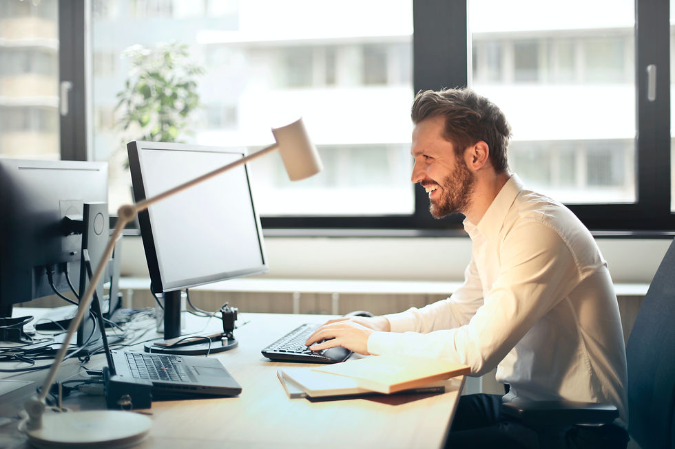 Smiling man working at a desk in front of a computer, representing productivity and success in the IT support sector.